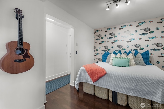 bedroom with track lighting, wood finished floors, and baseboards