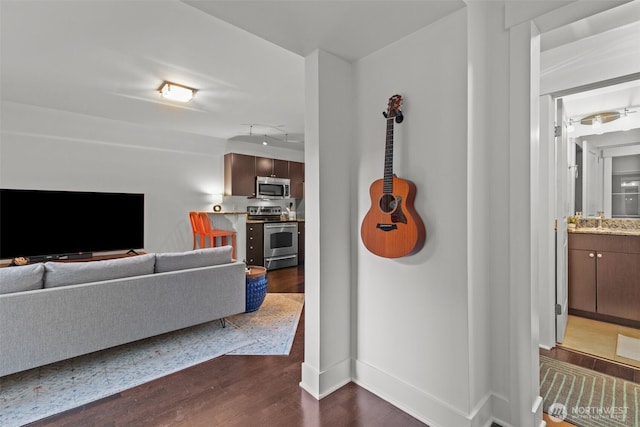 corridor featuring baseboards, a sink, and dark wood-style floors
