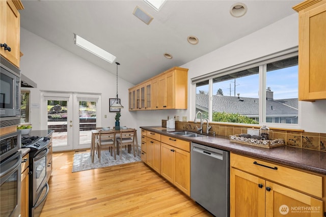 4538 Somerset Dr SE, Bellevue, WA 98006 - kitchen with a sink, dark countertops, stainless steel appliances, light wood-type flooring, and vaulted ceiling with skylight