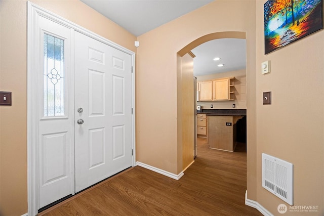 entryway with arched walkways, dark wood finished floors, baseboards, plenty of natural light, and recessed lighting