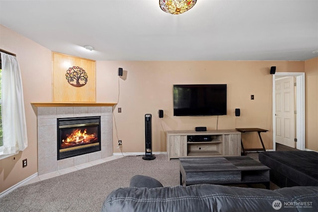 carpeted living room featuring a tiled fireplace and baseboards