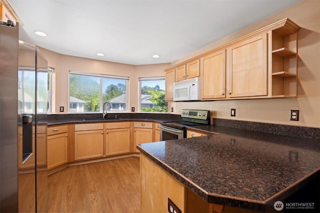 kitchen with white microwave, stainless steel electric stove, a sink, light brown cabinets, and light wood-style flooring