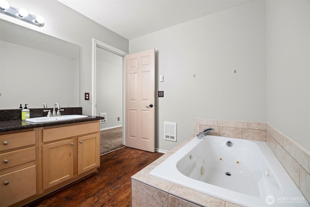 bathroom featuring wood finished floors, vanity, and a jetted tub
