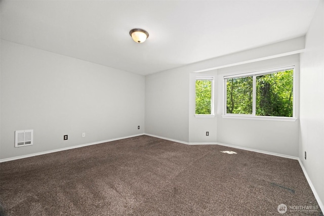 spare room featuring dark carpet and baseboards