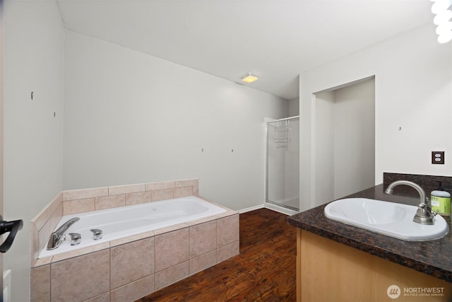 full bathroom with wood finished floors, a stall shower, a garden tub, and vanity