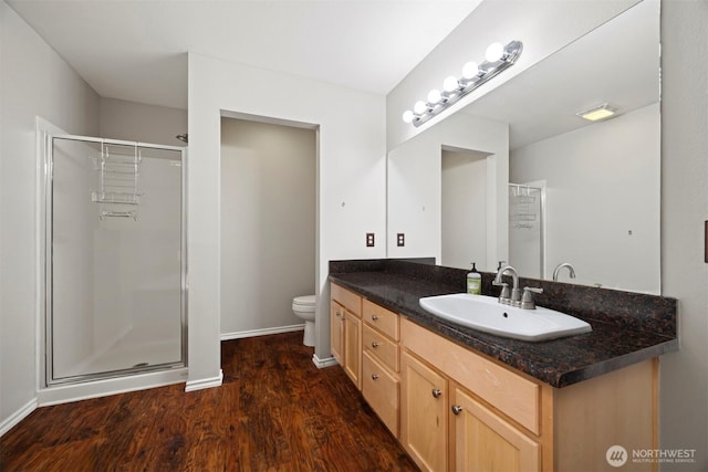 bathroom with a shower stall, wood finished floors, vanity, toilet, and baseboards