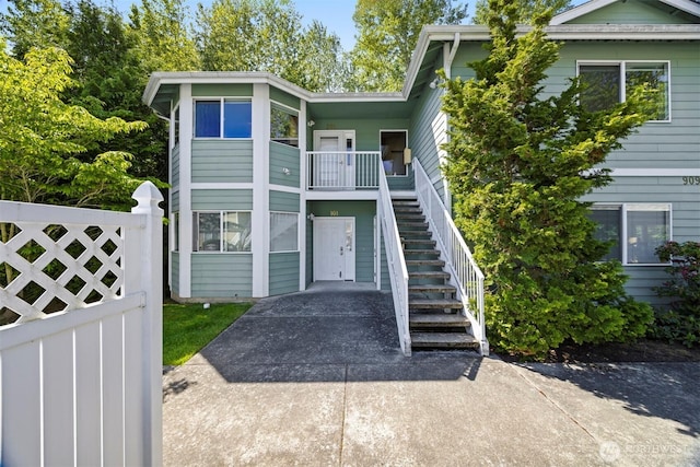 view of front facade with stairs, fence, and concrete driveway