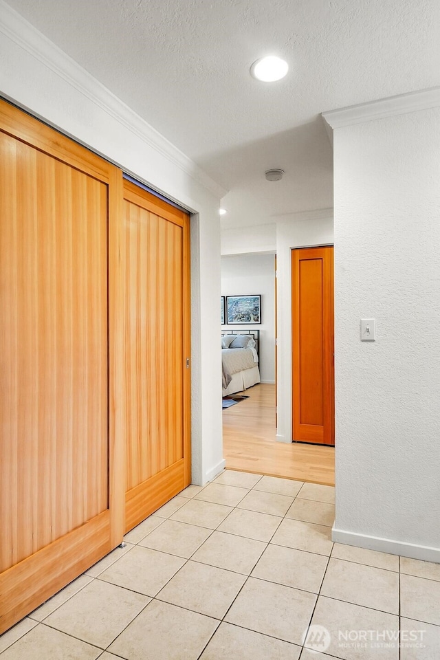 corridor with crown molding, a textured ceiling, light tile patterned floors, and recessed lighting