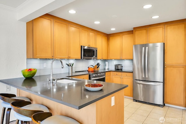 kitchen featuring a peninsula, a sink, dark countertops, backsplash, and appliances with stainless steel finishes