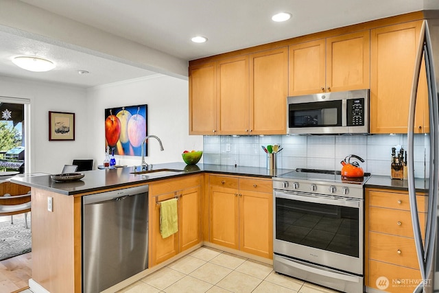 kitchen featuring a peninsula, a sink, dark countertops, stainless steel appliances, and decorative backsplash