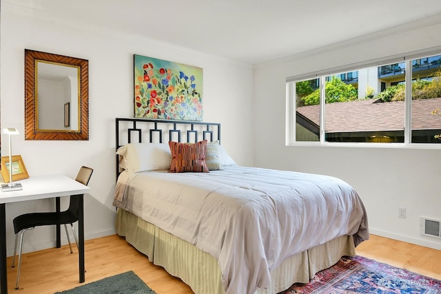 bedroom with ornamental molding, baseboards, visible vents, and wood finished floors