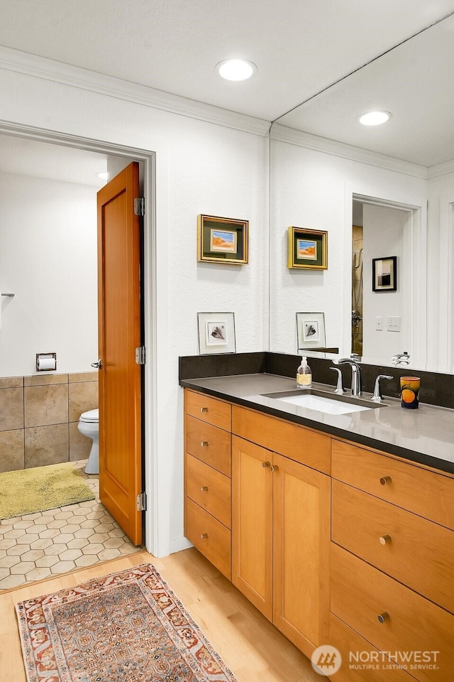 bathroom featuring toilet, wood finished floors, vanity, and ornamental molding