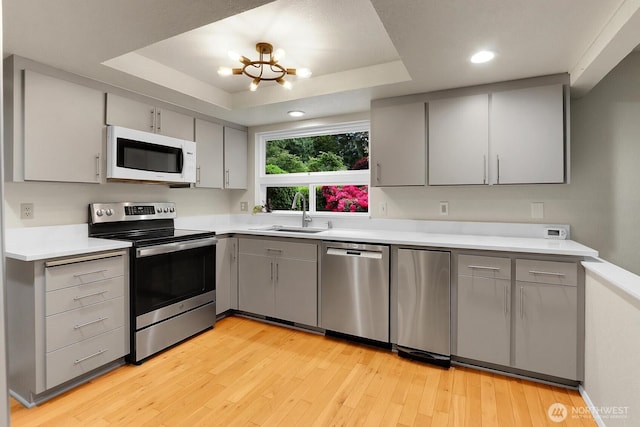19801 88th Ave W, Edmonds, WA 98026 - kitchen with stainless steel appliances, a sink, gray cabinetry, a raised ceiling, and light wood finished floors