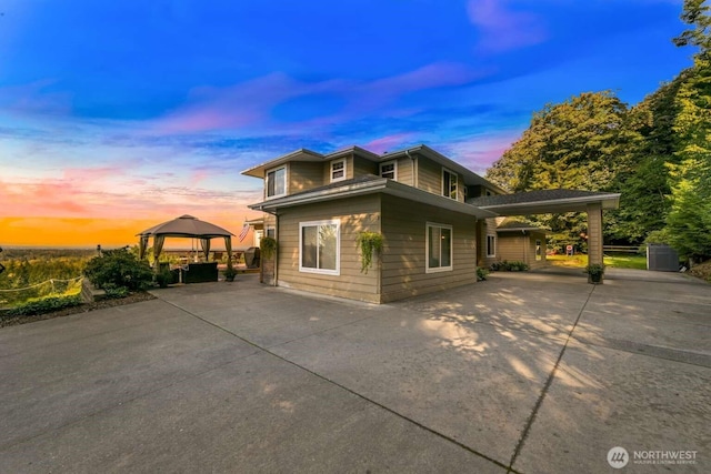 property exterior at dusk with a patio and a gazebo