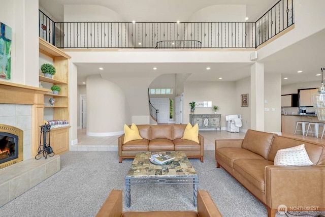 living room with a towering ceiling, carpet, a tiled fireplace, and built in features