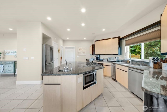kitchen with a center island with sink, appliances with stainless steel finishes, light tile patterned floors, and a sink