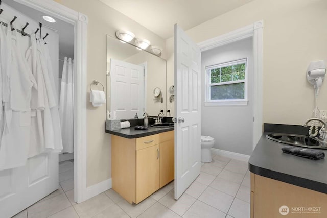 bathroom with vanity, toilet, baseboards, and tile patterned flooring