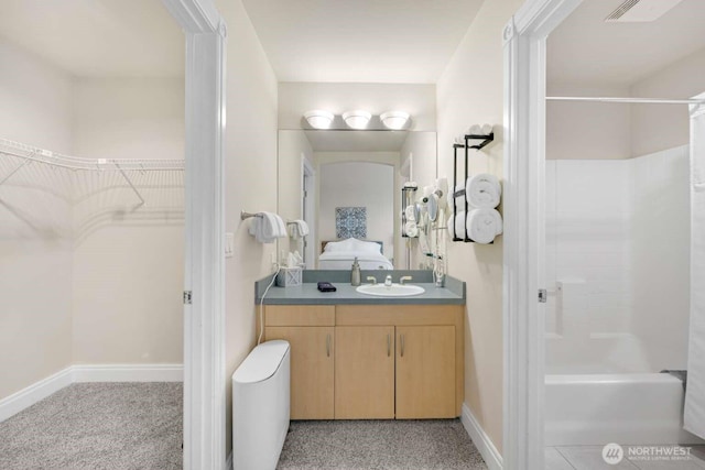 full bathroom featuring  shower combination, vanity, visible vents, a walk in closet, and baseboards