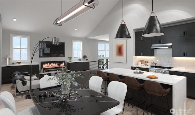 dining space with light wood finished floors, a glass covered fireplace, recessed lighting, and vaulted ceiling