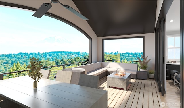 balcony with a wooded view, an outdoor living space, and a ceiling fan