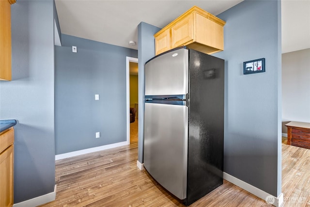 8075 Harborview Rd Unit 301, Blaine, WA 98230 - kitchen featuring freestanding refrigerator, light brown cabinetry, light wood finished floors, and baseboards