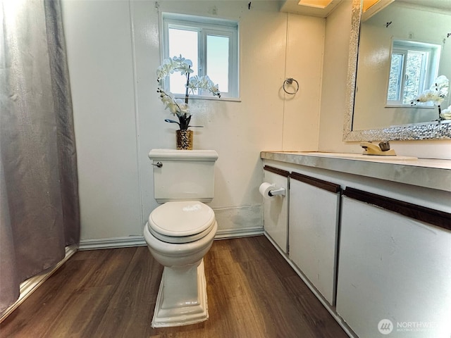 bathroom with wood finished floors, toilet, vanity, and baseboards