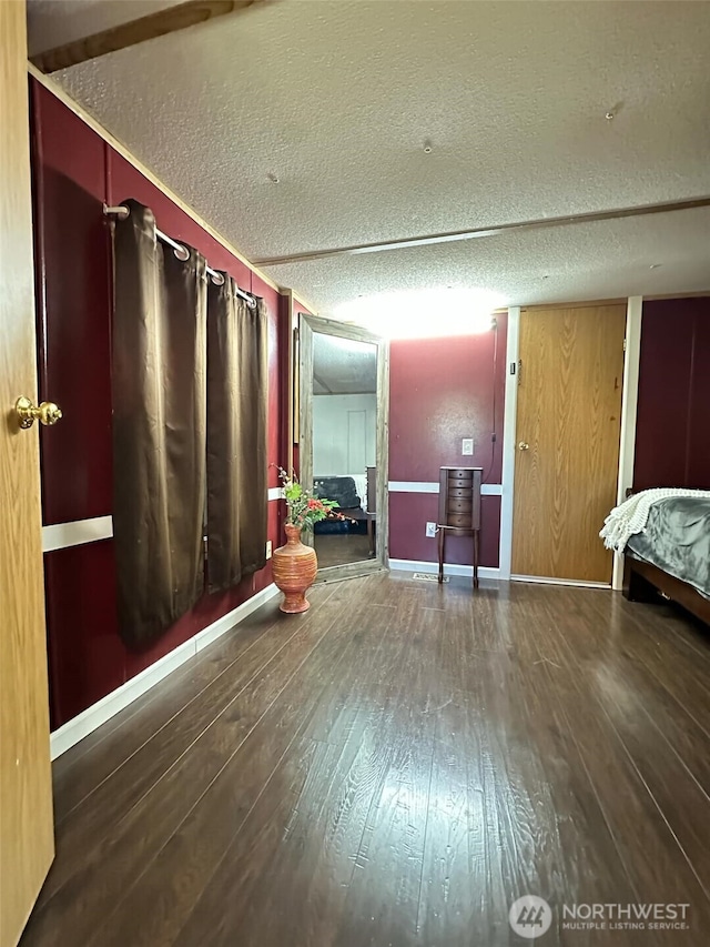 bedroom featuring wood-type flooring, a textured ceiling, and baseboards