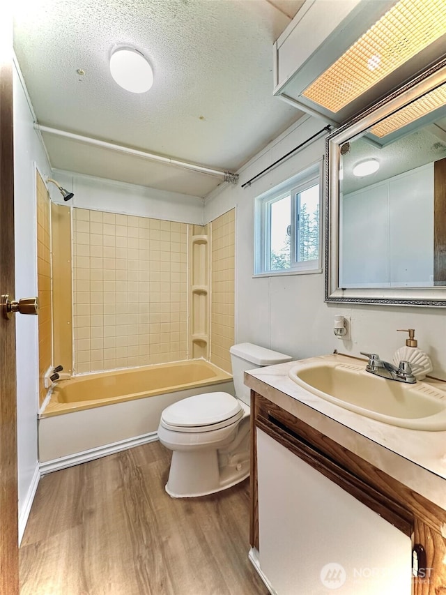 full bath featuring wood finished floors, shower / tub combination, toilet, vanity, and a textured ceiling