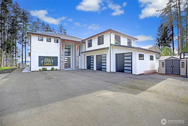 modern home featuring board and batten siding, a shed, a garage, and an outdoor structure