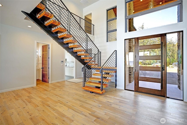 foyer featuring baseboards, stairs, a high ceiling, and hardwood / wood-style floors