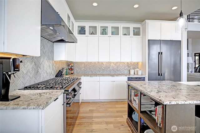 kitchen featuring white cabinets, decorative light fixtures, high end appliances, and ventilation hood
