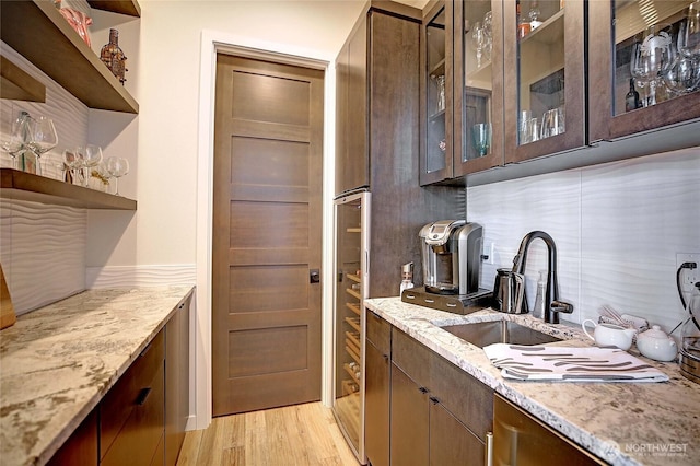 bar featuring backsplash, a sink, and light wood finished floors