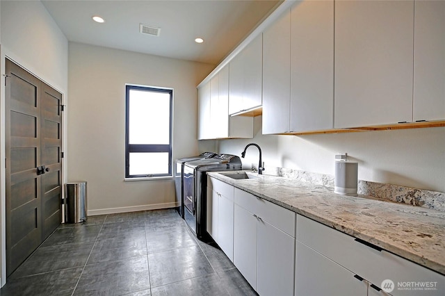 clothes washing area with visible vents, recessed lighting, washer and clothes dryer, a sink, and cabinet space