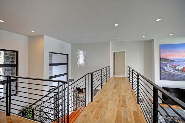 hall featuring recessed lighting, light wood finished floors, and an upstairs landing