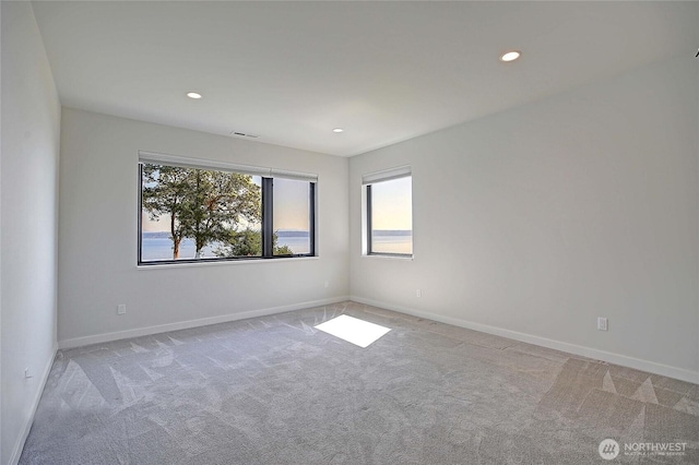 unfurnished room featuring recessed lighting, light colored carpet, and a healthy amount of sunlight