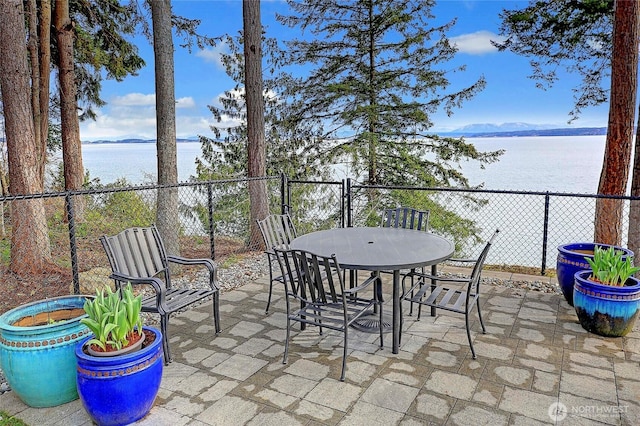 view of patio / terrace featuring a water view, fence, and outdoor dining space