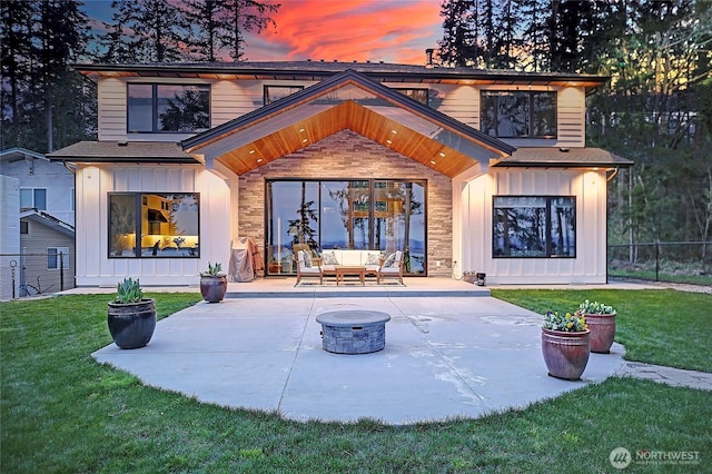 back of property featuring board and batten siding, a patio area, fence, and a lawn