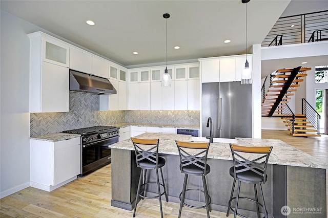 1699 SE Camano Dr, Camano Island, WA 98282 - kitchen with extractor fan, appliances with stainless steel finishes, light wood-style floors, a breakfast bar, and pendant lighting