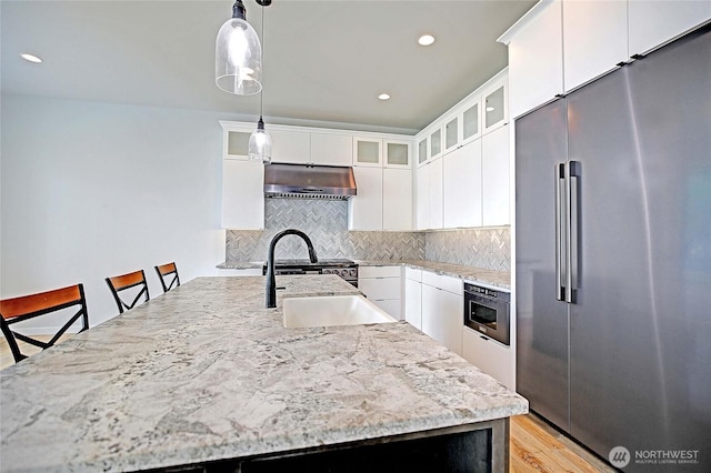1699 SE Camano Dr, Camano Island, WA 98282 - kitchen with high quality fridge, under cabinet range hood, tasteful backsplash, decorative light fixtures, and light stone countertops