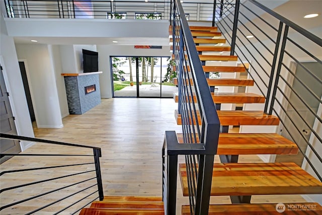 1699 SE Camano Dr, Camano Island, WA 98282 - stairs with a tiled fireplace, wood finished floors, a high ceiling, and recessed lighting