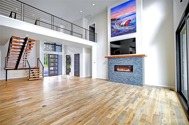 1699 SE Camano Dr, Camano Island, WA 98282 - unfurnished living room with stairway, wood finished floors, a towering ceiling, and a fireplace