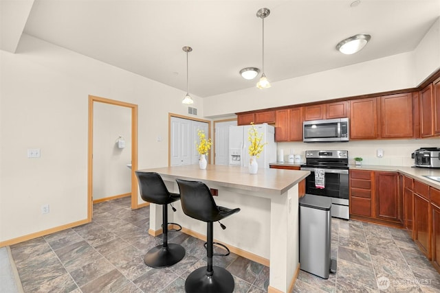 343 Tremont Ave Unit 102, Bellingham, WA 98226 - kitchen with brown cabinets, a breakfast bar area, light countertops, a center island, and appliances with stainless steel finishes
