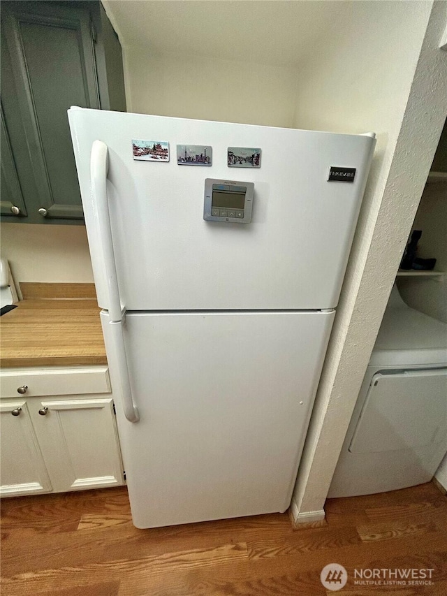 kitchen view of freestanding refrigerator, wood finished floors, and light countertops