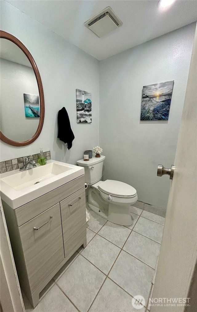 half bath featuring toilet, tile patterned floors, and vanity