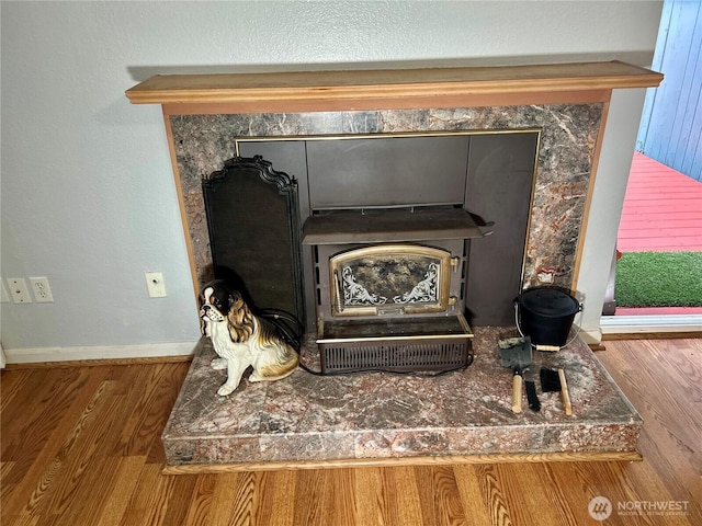 detailed view of wood finished floors, baseboards, and a wood stove