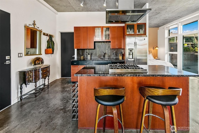 125 E Lynn St Unit 205, Seattle, WA 98102 - kitchen featuring appliances with stainless steel finishes, wall chimney range hood, backsplash, glass insert cabinets, and a breakfast bar area
