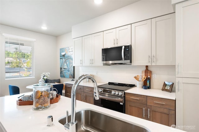kitchen with a sink, stainless steel appliances, tasteful backsplash, and light countertops