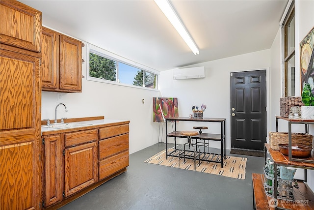 kitchen featuring a sink, a wall unit AC, brown cabinetry, concrete floors, and vaulted ceiling