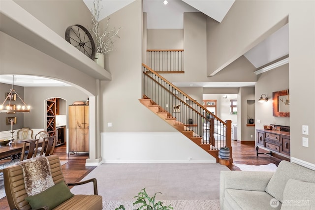 14028 104th Street Ct E, Puyallup, WA 98374 - carpeted living area with arched walkways, stairway, a high ceiling, baseboards, and wood finished floors