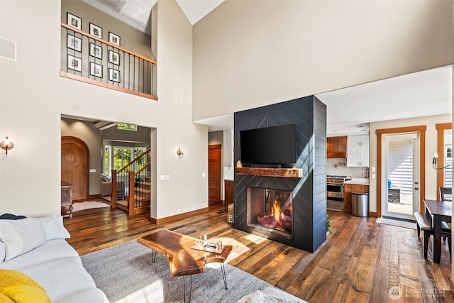 14028 104th Street Ct E, Puyallup, WA 98374 - living area with dark wood-style floors, a multi sided fireplace, a high ceiling, baseboards, and stairs